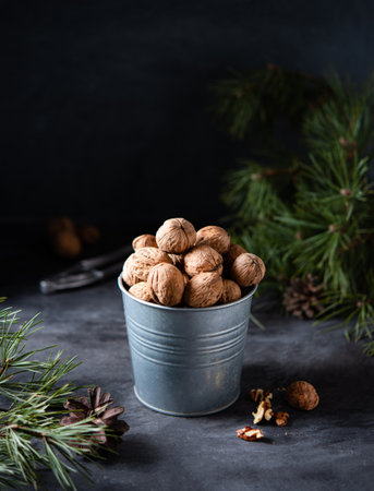 walnuts in a metal jar on a  dark wooden table among green Christmas tree. Front view and copy spaceの写真素材