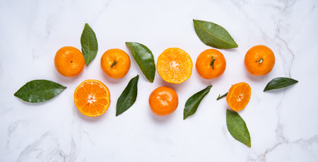 Flat lay sweet  tangerines and green leaves  on a white marble background. Top view and horizontal orientationの写真素材