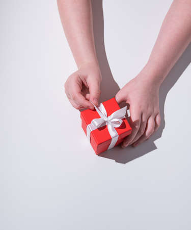 Childrens  hands open red holiday gift box with white ribbon. Top view and copy spaceの写真素材