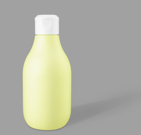 Mockup yellow biodegradable plastic cosmetic bottle on a trendy gray background. Front view and copy...