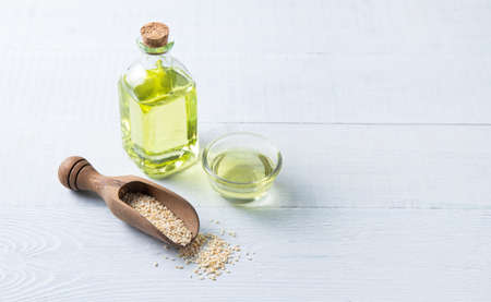 Natural vegetable oil from sesame seeds in a clear bottle on the wooden background. Dietary healthy food. Top view and copy spaceの写真素材
