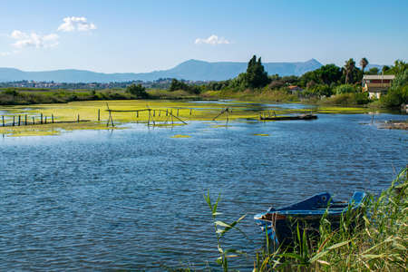 Summer lake with mud and blue boat on the coast of Corfu. The Ionian Archipelago. Greece. Europeの写真素材