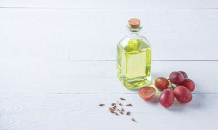 Natural vegetable oil from grape seeds in a clear bottle on the wooden background. Dietary healthy food. Copy spaceの写真素材