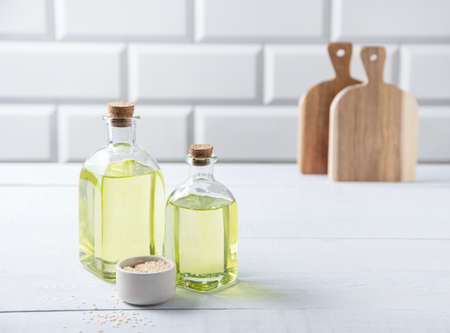 Natural vegetable oil from sesame seeds in a clear bottle on the white kitchen table. Dietary healthy food. Front view and copy spaceの写真素材
