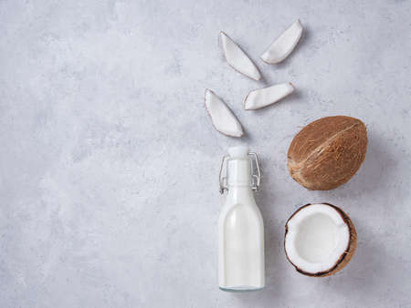 Healthy flat lay concept. Vegan milk bottle and coconut slices on gray background. Top  view and copy space imageの写真素材