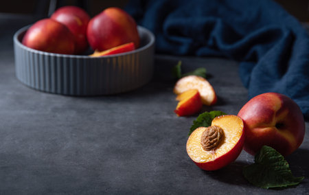 sweet nectarine in a gray  bowl and  slices on a dark  blue background. Low key concept and copy...
