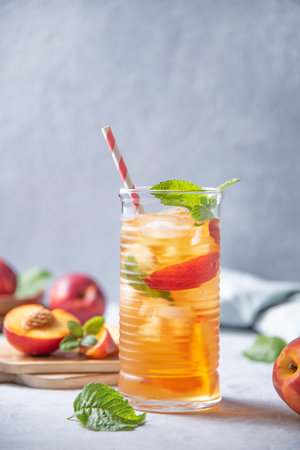 cool peach tea with mint and ice in a glass on a blue background. Vertical orientation.  Front view and copy space  imageの写真素材