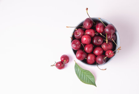 juicy red cherries in a gray bowl on a pink background. Top view and copy space image