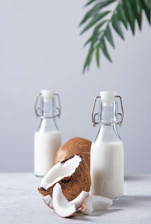 Two  vegan milk bottles on white marble table with half coconuts and palm branch. Front view and copy space imageの写真素材