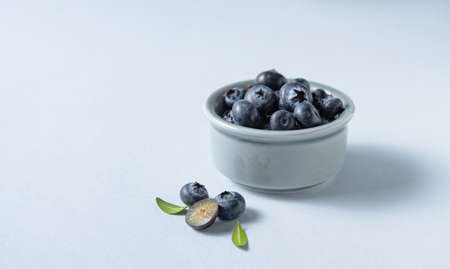 sweet fresh blueberries in a bowl  on a blue background. Macro and close up. Front view and copy space imageの写真素材