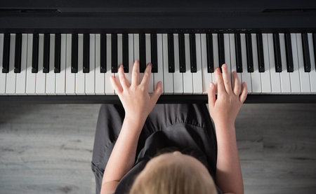 a girl in a gray dress plays an electronic piano. Home schooling. Top view image