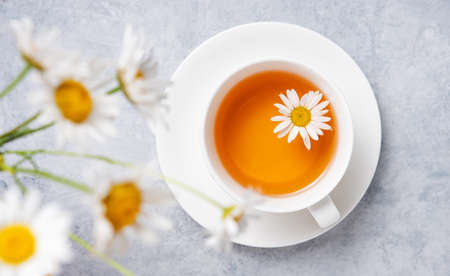 chamomile tea in a white cup with flowers daisy  on a blue background. Top view and close up imageの写真素材