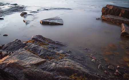 Beautiful ssurface on the shore of the White Sea  with stones and seaweed at sunny morning Belomorsk, Karelia. Long exposure imageの写真素材