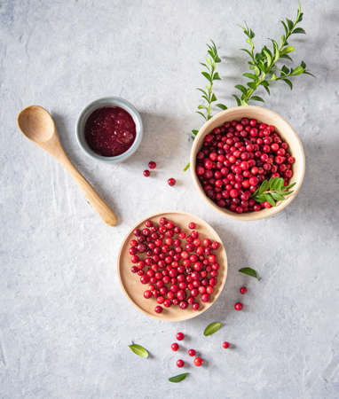 juicy forest lingonberry with handmade jam  in a wooden bowl on white table. Concept homemade healthy food. Top view and copy space imageの写真素材