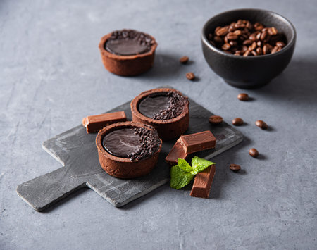 Sweet mini chocolate tarts with coffee beans on a gray backgroundの写真素材