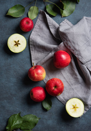 Juicy red apples with leaves on a gray napkin on a dark blue background. The concept of autumn healthy food. Top view.の写真素材