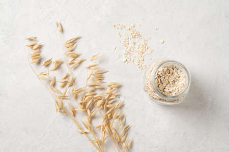 oat flakes in a jar with oats dry brunch on a white textured background. Raw and vegan product. Natural food. Top view and copy space.の写真素材