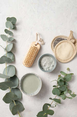 Organic cosmetic green clay,  brush, sponge  and eucalyptus branch on a white textured background. The concept of spa and wellness. Top view and copy space.の写真素材