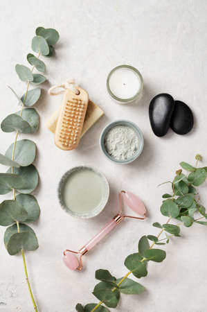 Organic cosmetic clay,  brush,  massage stone  and eucalyptus branch on a white textured background. The concept of spa and wellness. Top view.の写真素材