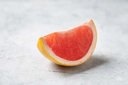 Juicy red grapefruit slice on a blue background close up. Concept healthy and diet food. Macro and copy space.の写真素材