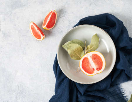 juicy red grapefruit in a plate and slices on a blue background with a dark napkin. Concept healthy food. Top view and copy space.の写真素材
