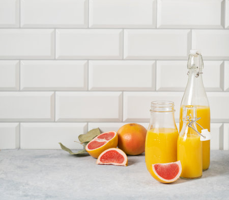 juicy grapefruit and bottled juice on a blue table on  a white brick background. Front view and copy space.の写真素材