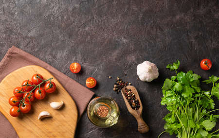 Spices and fresh herbs parsley, garlic, pepper, tomatoes and oil on a dark brown background. The concept of delicious and healthy food. Top view and copy space.の写真素材