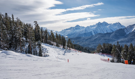 Beautiful landscape of the Arkhyz ski resort with mountains, snow, forest, skiers and snowboarders  on a sunny winter day. Caucasus  Mountains, Russia.の写真素材