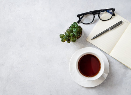 Flat lay cup of tea, notepad, pen, eyeglass and succulent plant on a light  background. Work women's concept. Top view and copy space.の写真素材