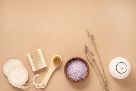 Organic sea salt for the body with dry lavender flowers, sponge, brush, soap and candle on a beige background. Skin care. The concept of a natural and eco-friendly spa product. Top view, copy space.の写真素材