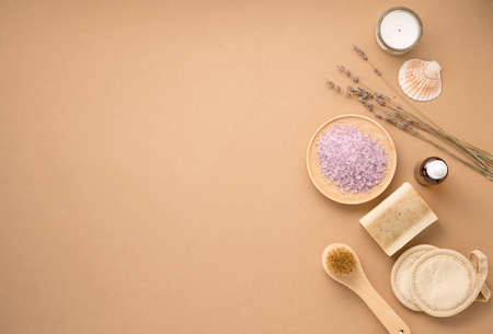 Organic sea salt for the body with dry lavender flowers, sponge, brush, soap and candle on a beige background. Skin care. The concept of a natural and eco-friendly spa product. Top view, copy space.の写真素材