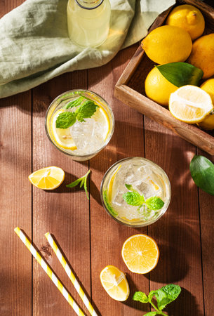 Two glasses of Lemonade drink with fresh lemons. Refreshing cocktails with lemon, mint and ice on...