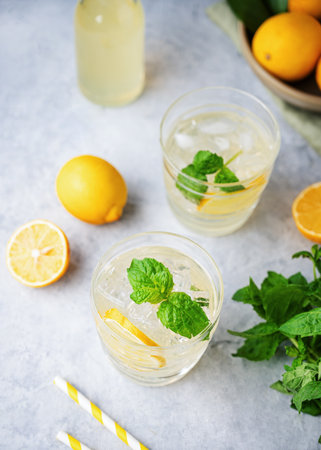 Lemonade soda drink with fresh lemons. Refreshing cocktail with lemon, mint and ice on blue background. Summer cold drinks concept. Top view.の写真素材