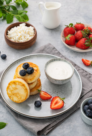 Cottage cheese pancakes with mint, blueberries, strawberries and milk on a gray  background. Healthy and delicious breakfast.の写真素材