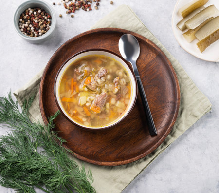 Traditional Russian soup with pickled cucumbers. Pickle with pearl barley and meat on a light background with fresh dill and spices. Top viewの写真素材