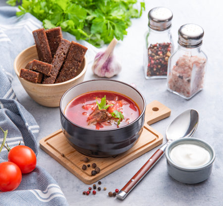 Borsch soup with beetroot,  meat and sour cream in a bowl on a light background with croutons and fresh herbs. The concept of traditional healthy Ukrainian food.の写真素材