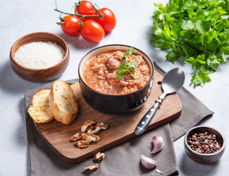 Thick beef or lamb kharcho soup with rice, tomato, walnuts and spices in a bowl on a light background with fresh tomatoes, herbs and bread. A traditional dish of Caucasian folk food.の写真素材