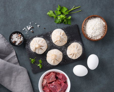 Georgian Khinkali dumplings with meat, herbs and spices on a board not cooked on a dark background. Top view.の写真素材
