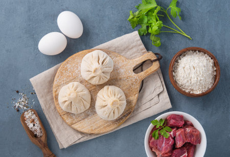 Georgian Khinkali dumplings with meat, herbs and spices on a wooden board not cooked on a blue background. Top view.の写真素材