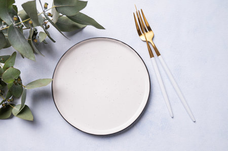 Festive table setting for a spring celebration, wedding, birthday or mother's day with eucalyptus branches on a light background. The concept of the restaurant menu. Top view and place to copy.の写真素材