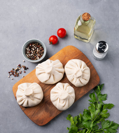 Georgian Khinkali dumplings with meat, herbs and spices on a wooden board not cooked on a blue background. Top view and copy space.の写真素材
