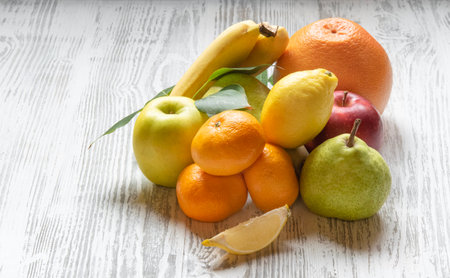 Fresh farm fruits. Apples, pears, oranges, bananas and tangerines on a dark wooden background. The concept of healthy vegetarian food from the market. Copy space.の写真素材