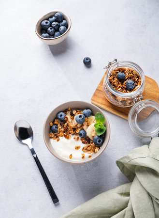 Muesli with vegetarian yogurt, banana and blueberries in a bowl on a light background. Healthy and dietary homemade granola for breakfast. Top view and copy space.の写真素材