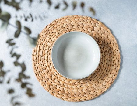 Table setting with ceramic plate and eucalyptus branches on blue background. Minimal style concept. Top viewの写真素材