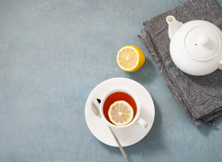 A cup of herbal tea with lemon and teapot on a blue  background. Healthy and detox  drink concept for breakfast. Top view and copy space.の写真素材