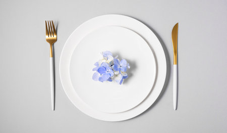 Festive table setting with blue hydrangea flowers and white plates on a light background. The concept of celebrating women's day, birthday or mother's day. Top view and copy space.の写真素材