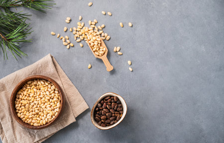 Pine nuts in a bowl  on napkin and scattered on a blue background with branches of pine needles. The concept of natural, organic and healthy superfoods and snacks.  Top view and copy space.の写真素材