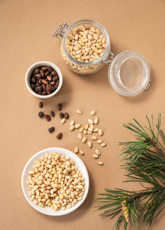 Pine nuts in a bowl and jar on a yellow background with branches of pine needles. The concept of natural, organic and healthy superfoods and snacks. Top view.の写真素材