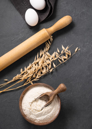 Oatmeal, eggs and rolling pin on a dark  background. Organic baking ingredients. Concept of homemade and healthy food. Top view.の写真素材