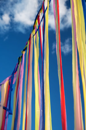 Multicolored ribbons or garlands flutter in the wind on a summer sunny day with a blue sky with...
